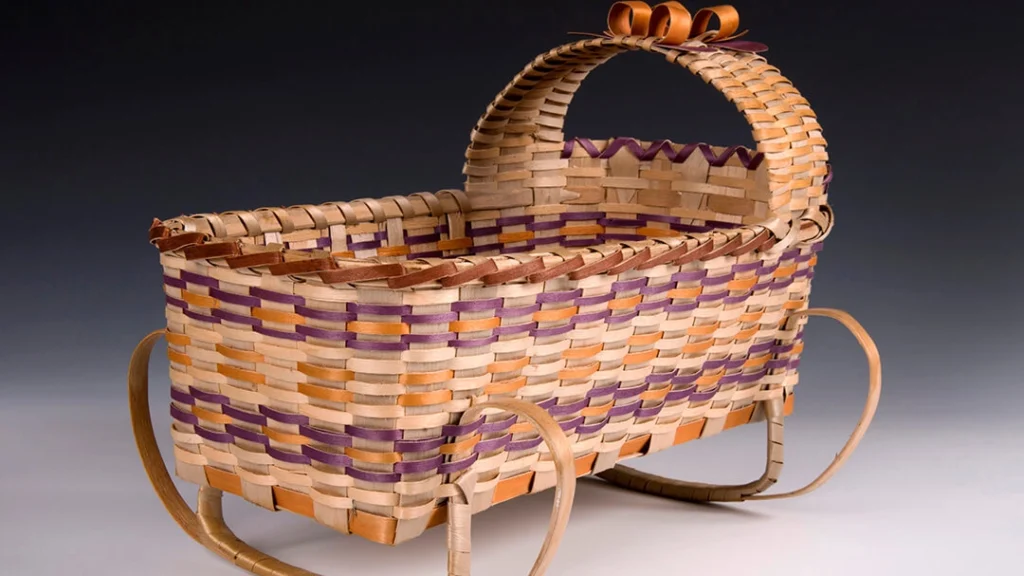 A rocking doll cradle basket, creation attributed to Christine Hall.