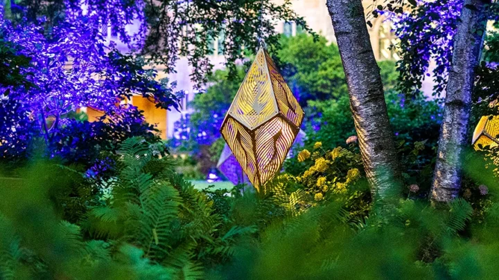 Metal geometric sculptures surrounded by blooming gardens.