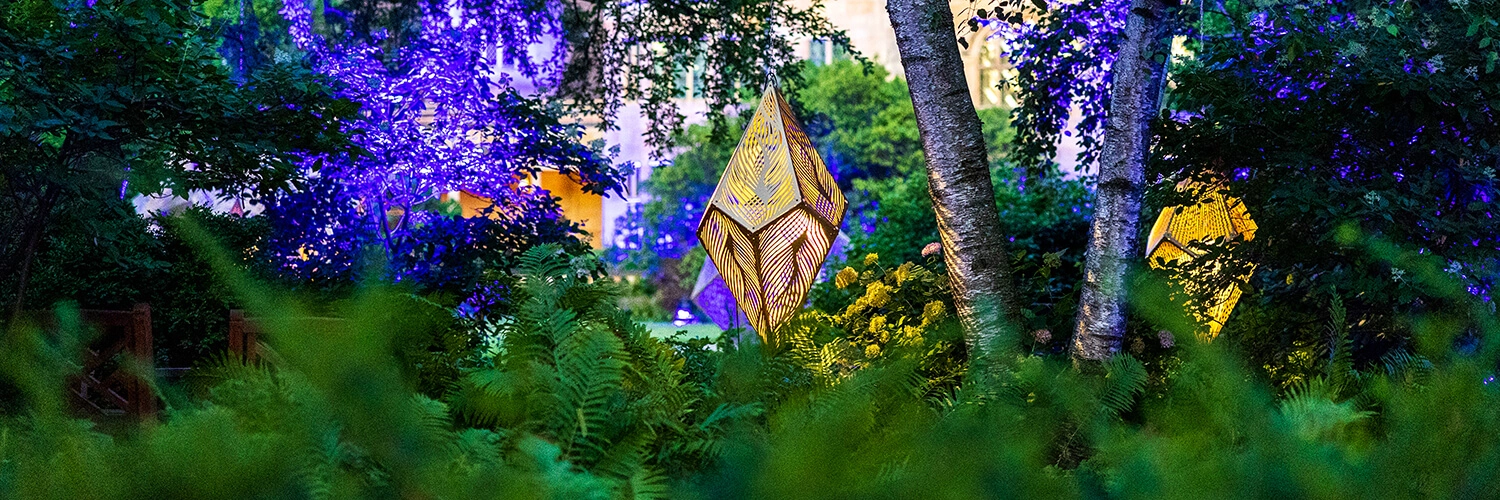 Metal geometric sculptures surrounded by blooming gardens.