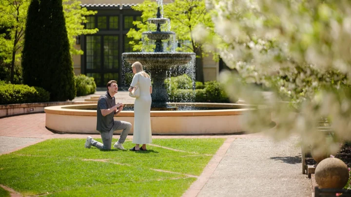 A young man proposes to a young woman in the Formal Garden at the Paine.
