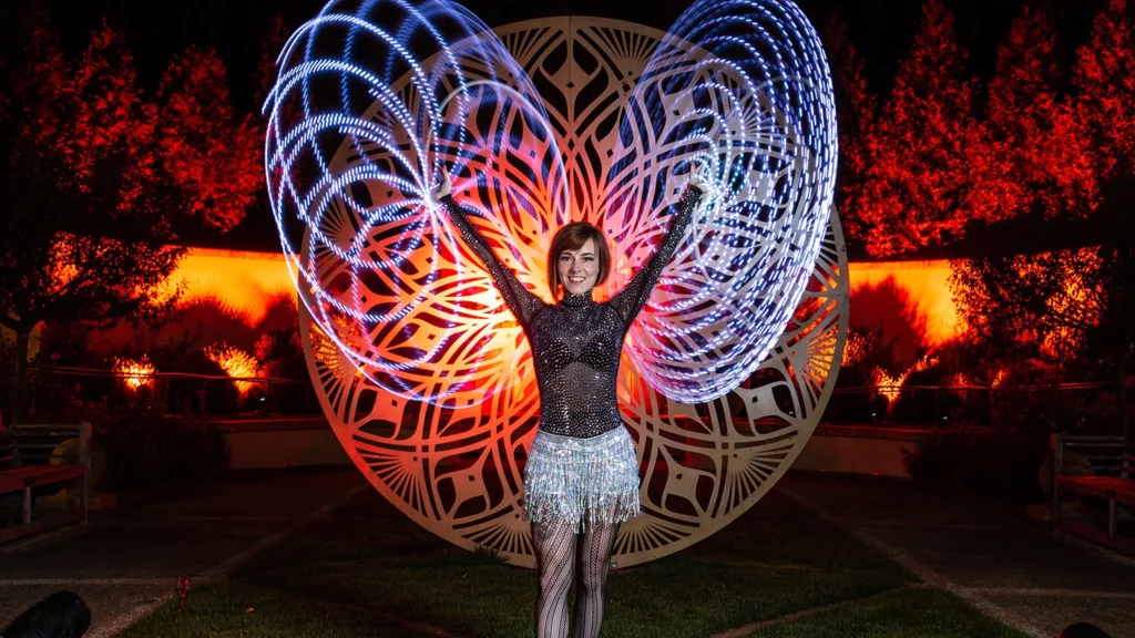A light dancer performs in the garden at night.