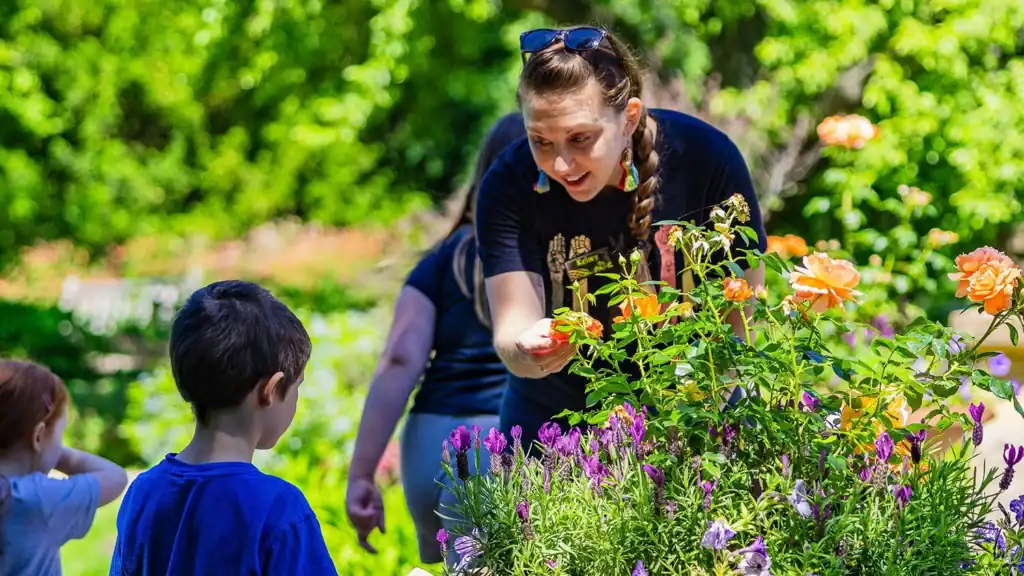 A Paine staff member showing a flower to a child.