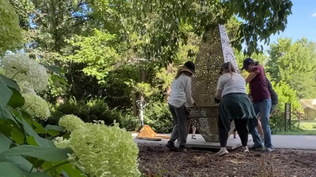 Paine staff members move a sculpture in the gardens